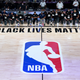 Members of the New Orleans Pelicans and Utah Jazz kneel before a Black Lives Matter logo before the start of their game at HP Field House at ESPN Wide World Of Sports Complex on July 30, 2020 in Reunion, Florida.